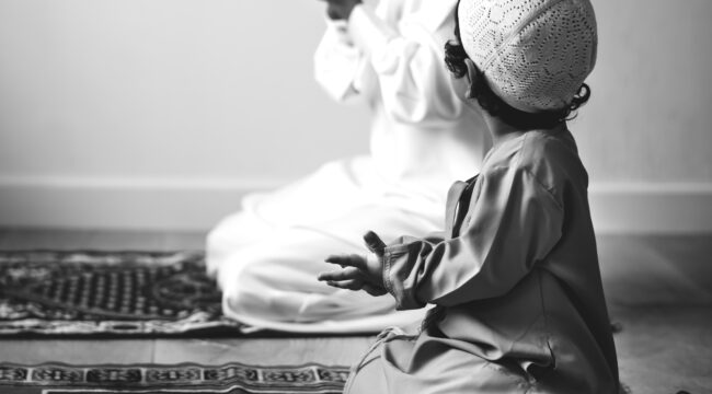 Muslim boy learning how to make Dua to Allah